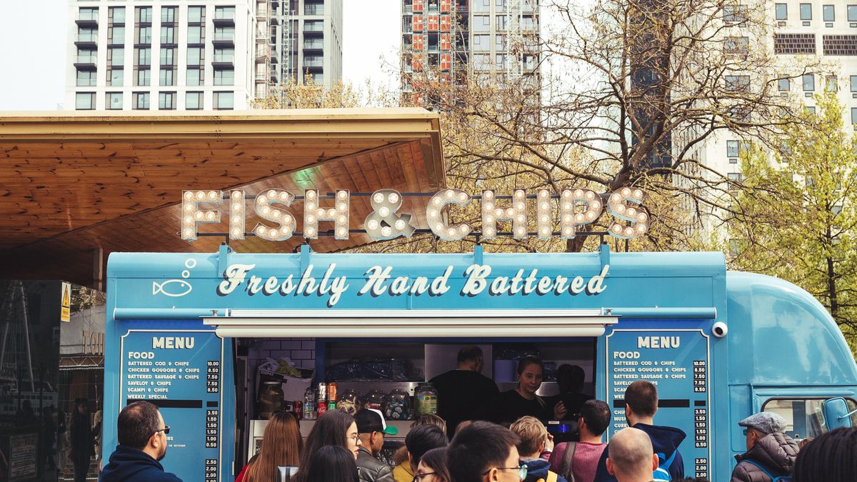 Foule attablée devant un food truck lors d'un événement en extérieur en ville