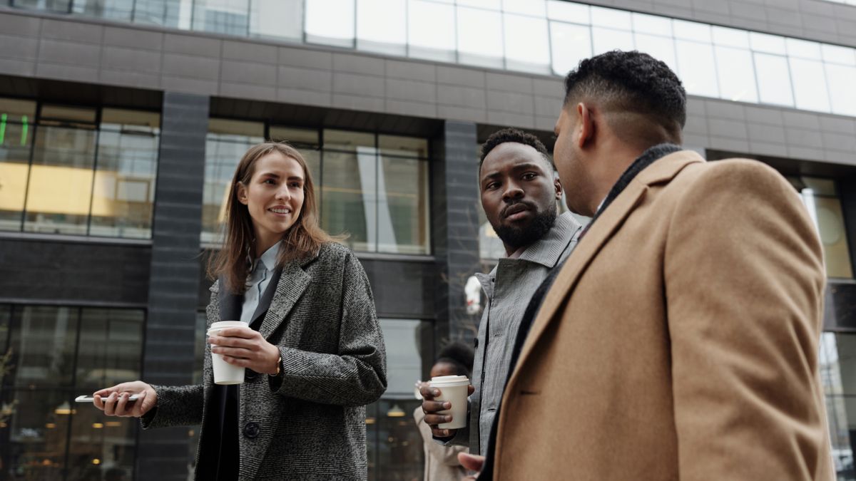 Groupe de collaborateurs échangeant en extérieur pendant une pause professionnelle